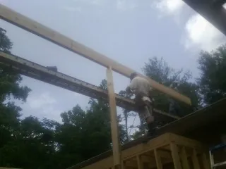 Carpenter setting a ridge beam over a new addition frame — Ice Dam Removal by Roofing Brothers in Mc Kenney