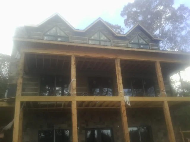Dormers and porch framing on a large log home under construction — Roof Coating work by our crew in Mc Kenney