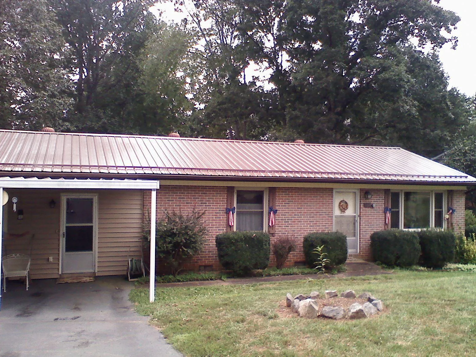 Bronze metal roof and carport on a brick ranch home — Roof Repair work by our crew in Mc Kenney